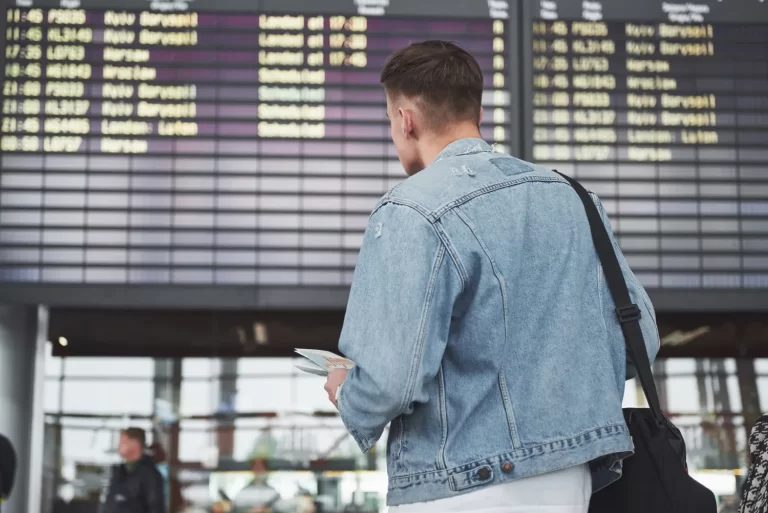 Homem de costas observando o painel de voos no aeroporto